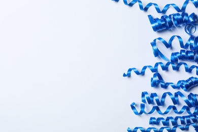 Photo of Blue serpentine streamers on white background, top view