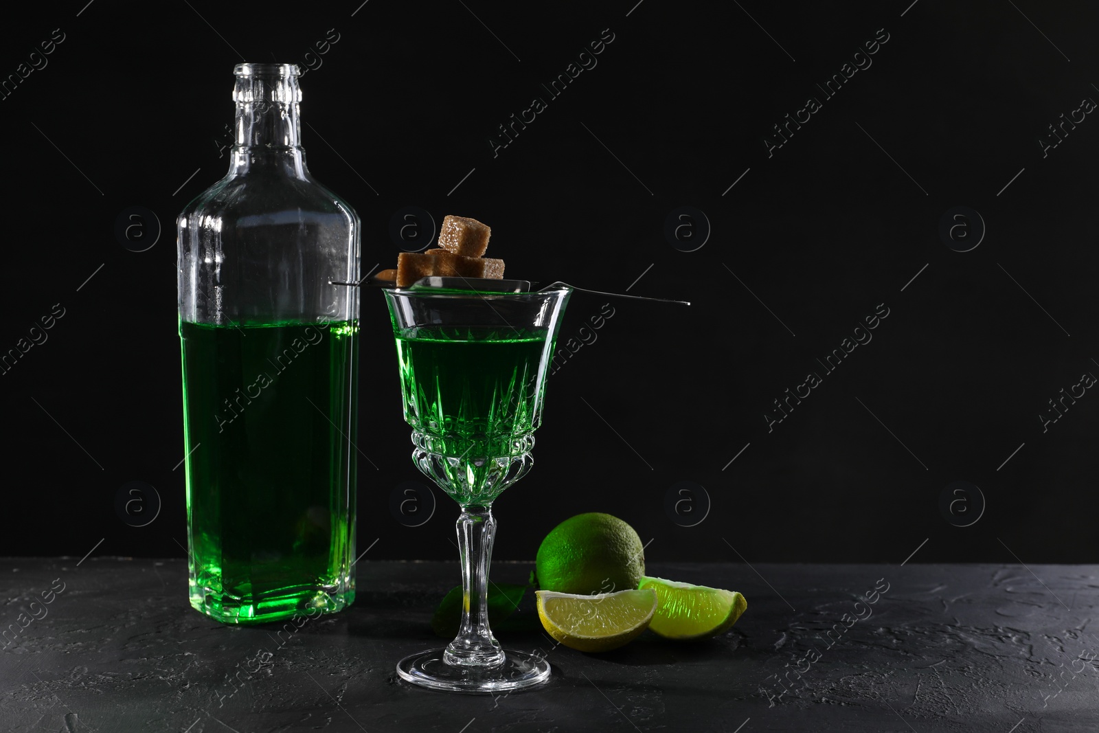 Photo of Absinthe, brown sugar and lime on black table, space for text. Alcoholic drink