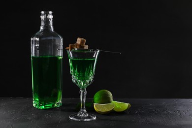 Photo of Absinthe, brown sugar and lime on black table, space for text. Alcoholic drink