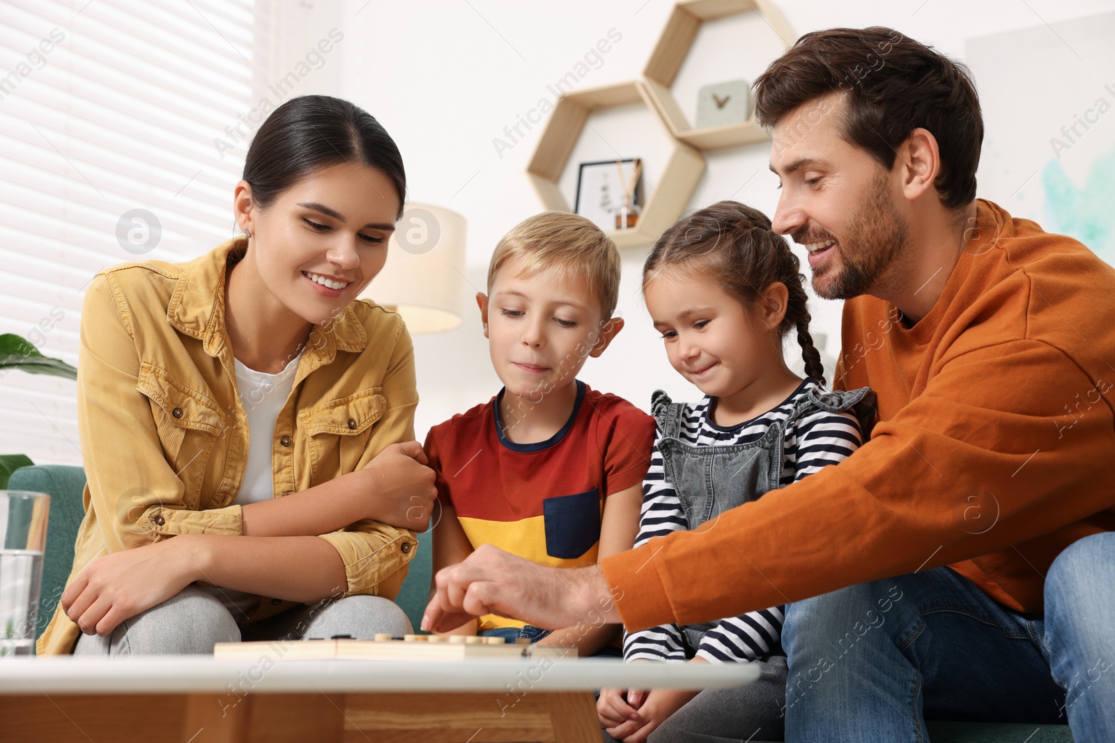 Photo of Family playing checkers at coffee table in room