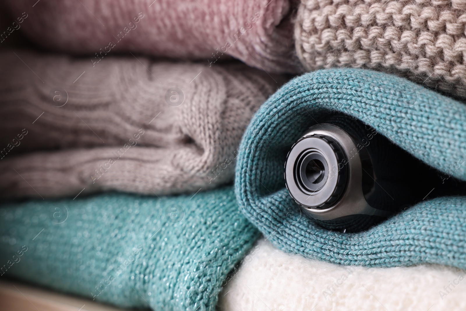 Photo of Camera hidden between clothes in wardrobe closet, closeup. Space for text