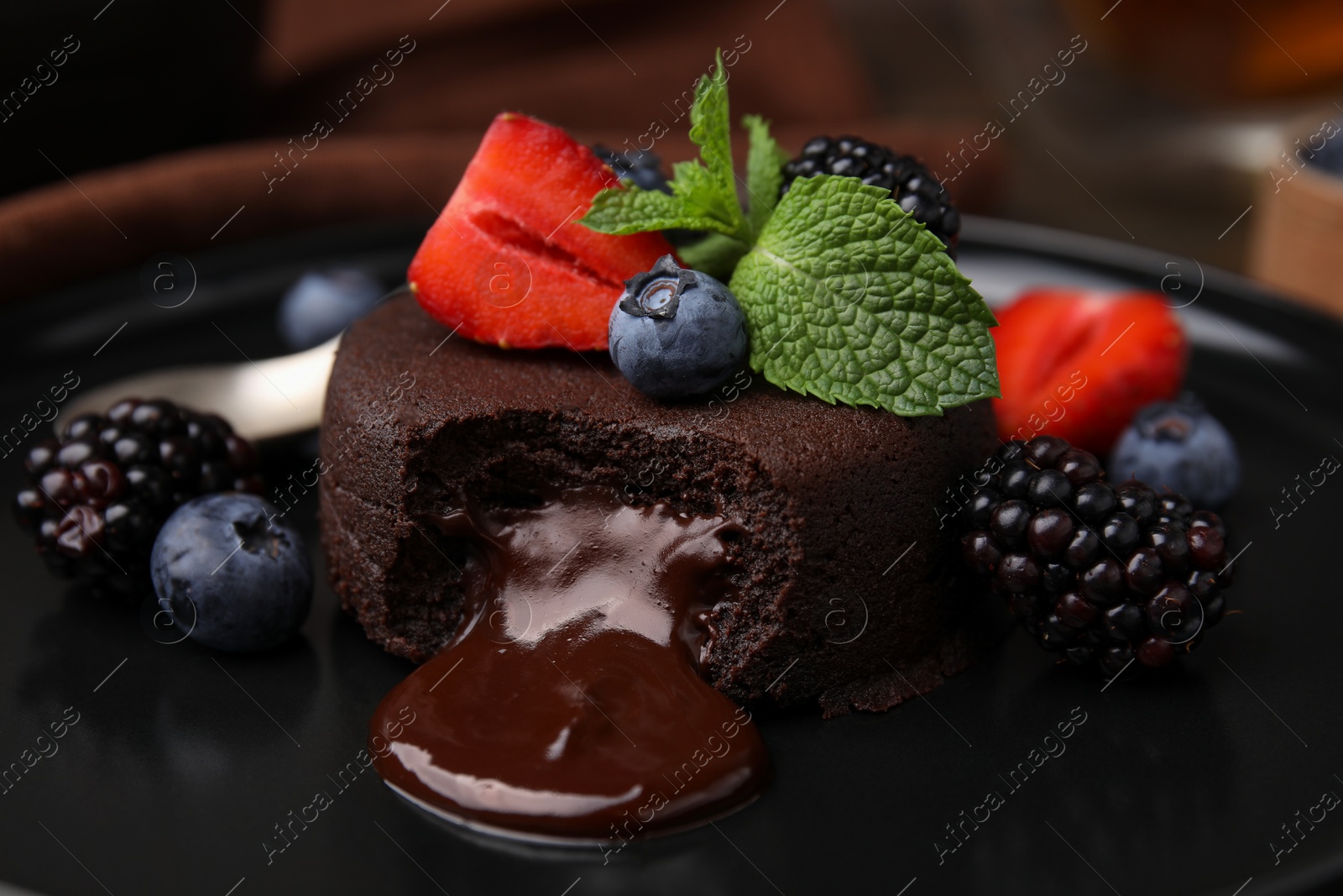 Photo of Delicious chocolate fondant, berries and mint on plate, closeup