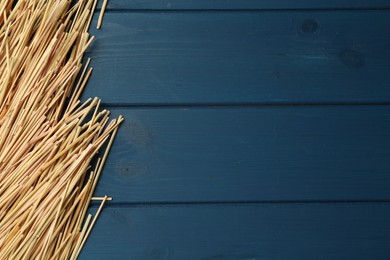 Heap of dried hay on blue wooden background, flat lay. Space for text