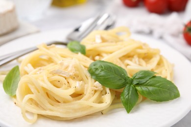 Delicious pasta with brie cheese and basil leaves on table, closeup