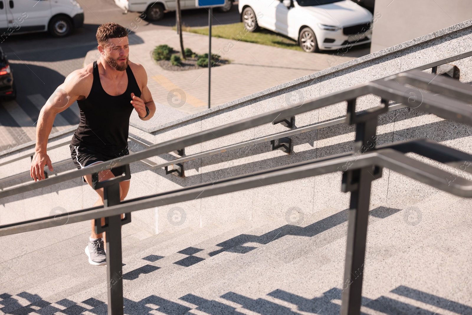 Photo of Man running up stairs outdoors on sunny day. Space for text
