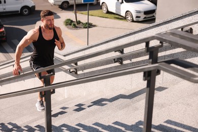 Man running up stairs outdoors on sunny day. Space for text