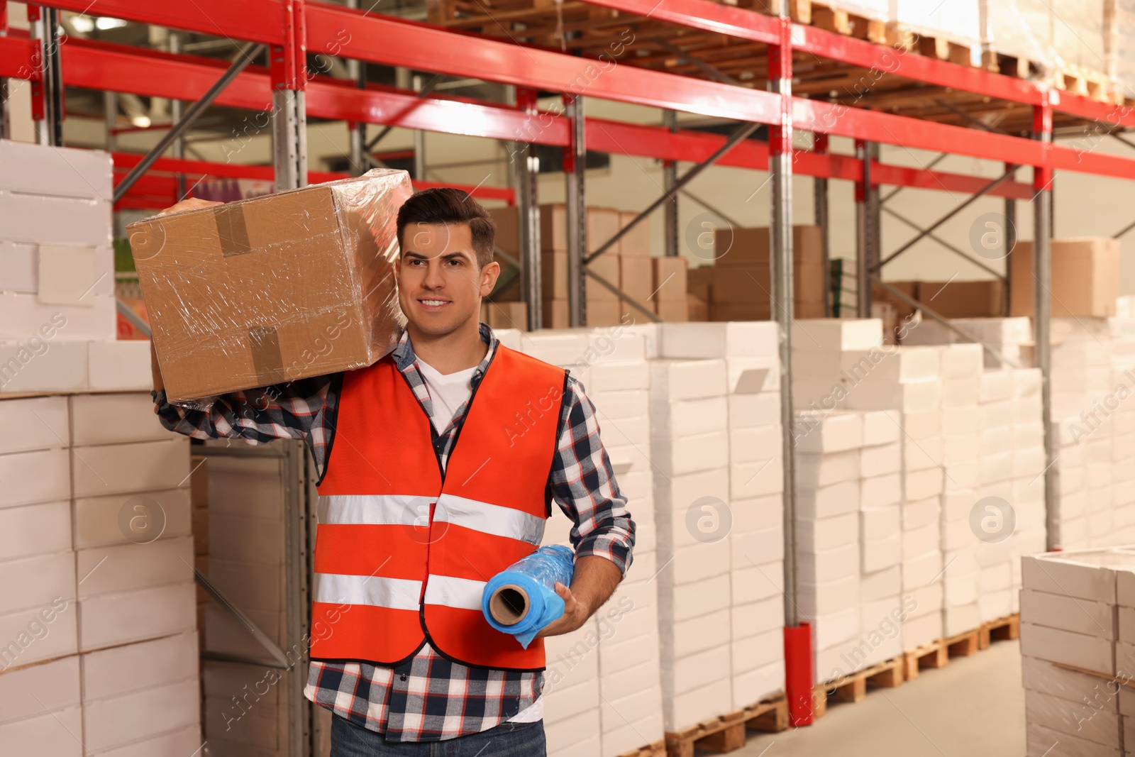 Photo of Worker with roll of stretch film and wrapped box in warehouse