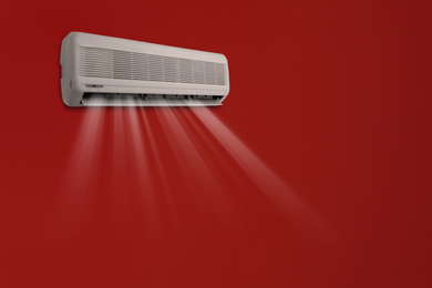 Image of Modern air conditioner on red wall indoors