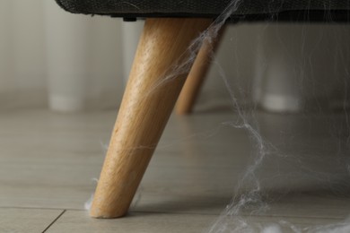 Photo of Old cobweb on chair in room, closeup