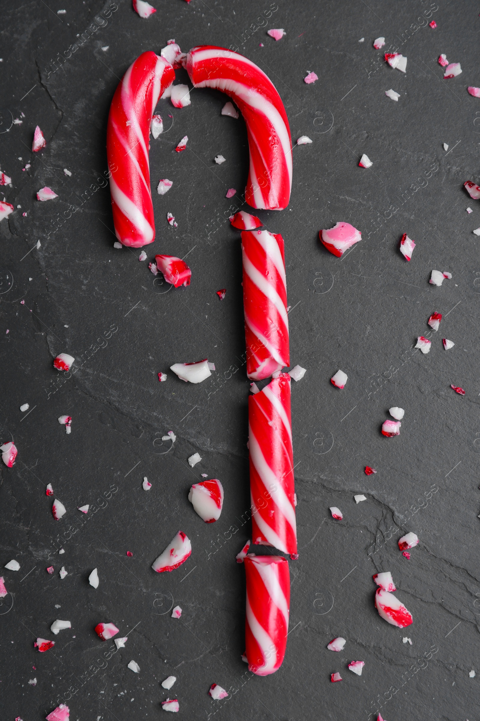 Photo of Crushed Christmas candy cane on black background, flat lay