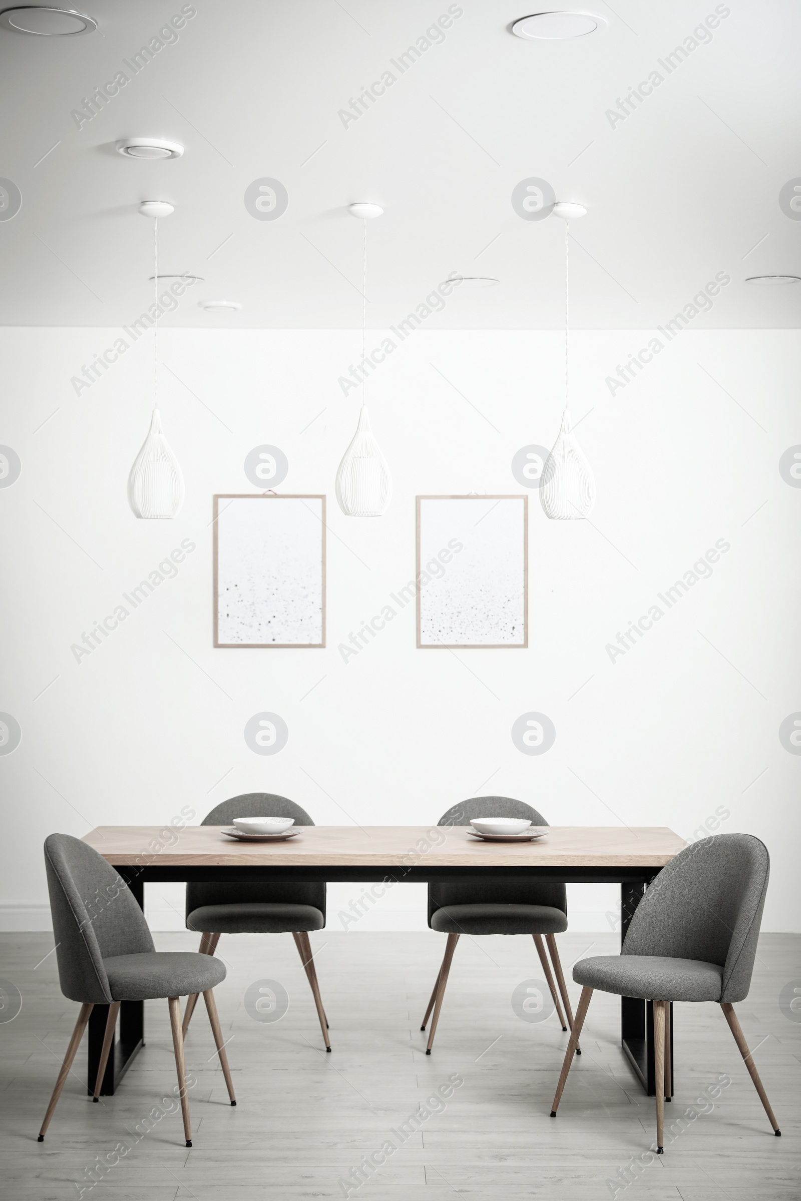 Photo of Stylish wooden table and chairs in light room. Modern interior design