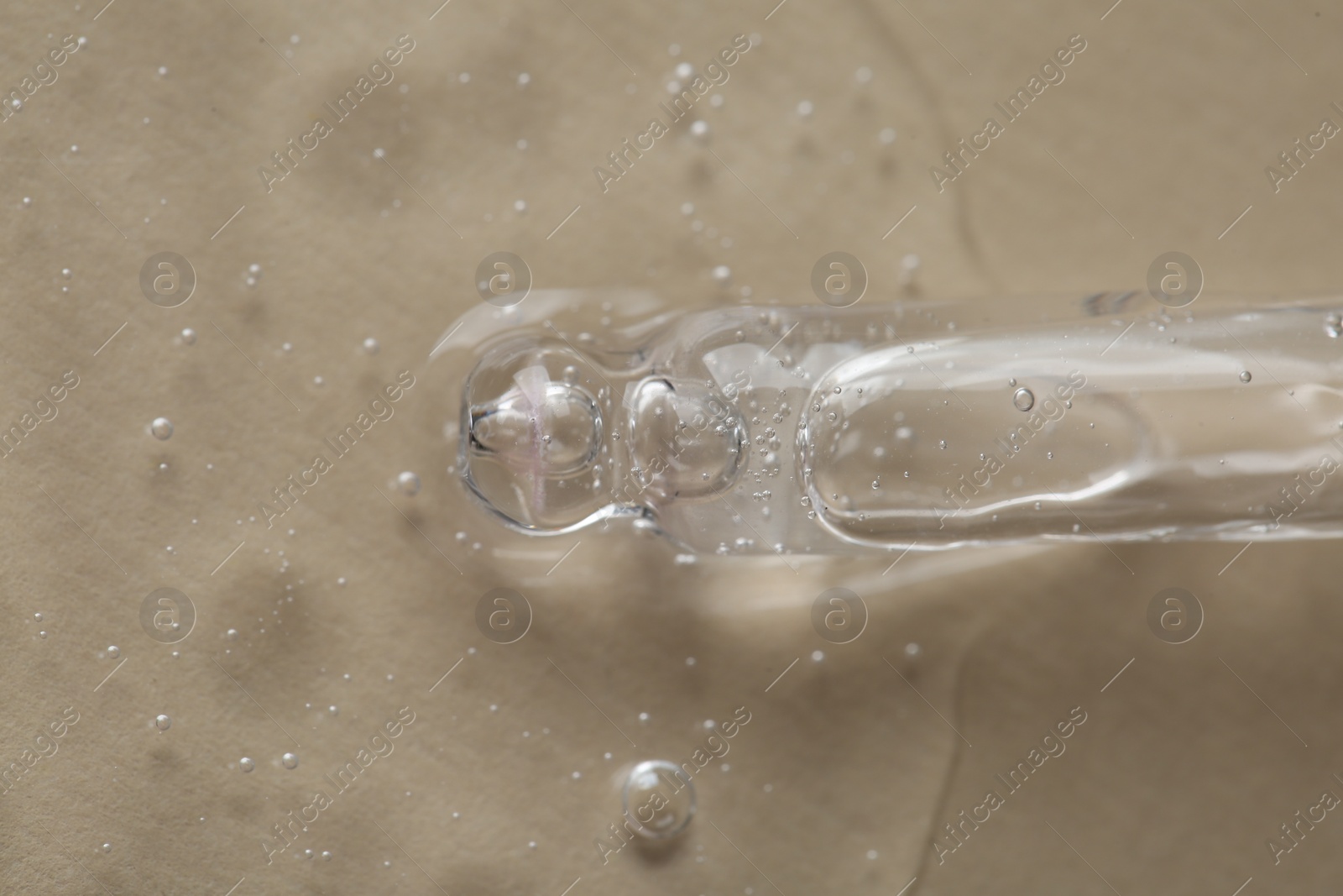 Photo of Pipette with cosmetic serum on beige background, macro view