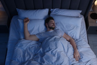 Photo of Man sleeping in bed at night, above view