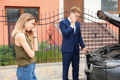 Photo of Young man and woman near broken car outdoors