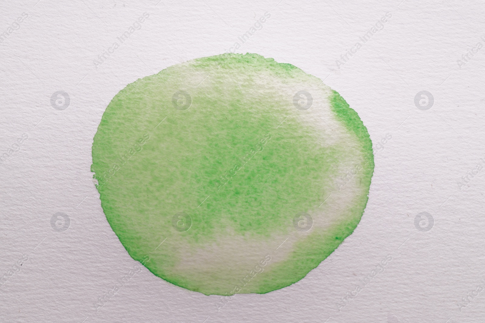 Photo of Blot of green watercolor paint on white paper, top view