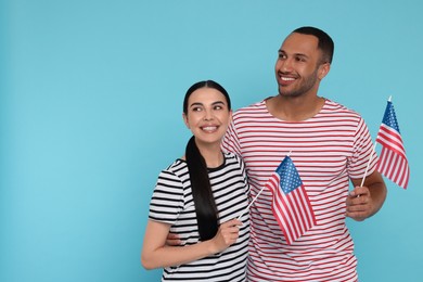 4th of July - Independence Day of USA. Happy couple with American flags on light blue background, space for text