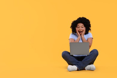 Emotional young woman with laptop on yellow background. Space for text