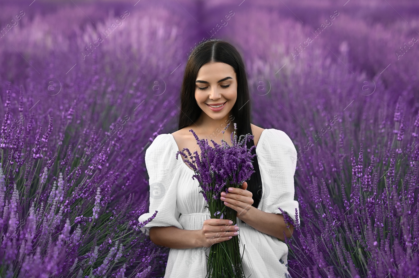 Photo of Beautiful young woman with bouquet in lavender field