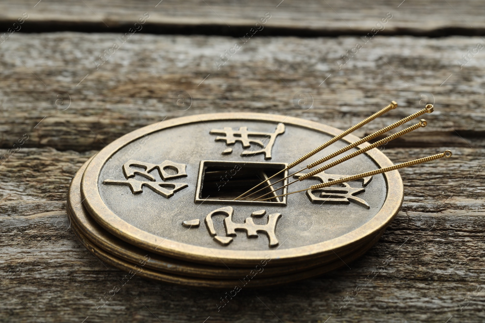 Photo of Acupuncture needles and stacked Chinese coins on wooden table, closeup