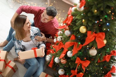 Photo of Young couple with Christmas gift at home