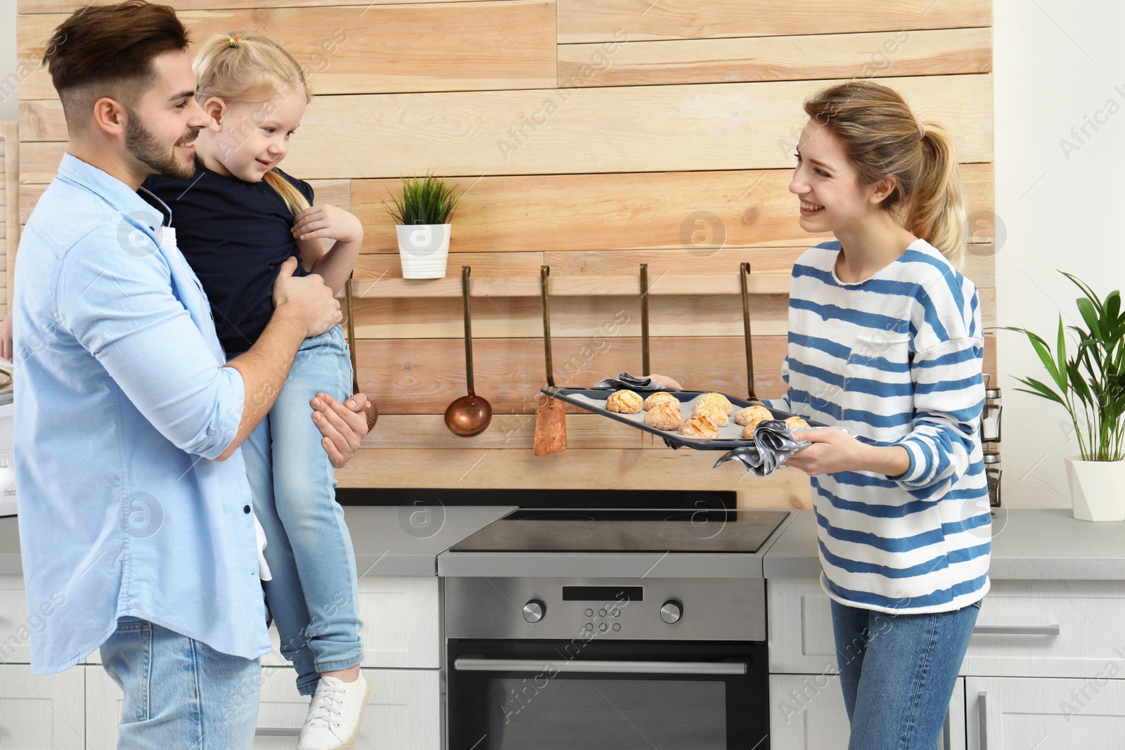 Photo of Young woman treating her family with homemade oven baked cookies in kitchen