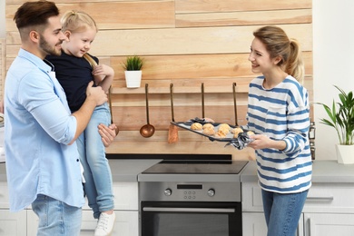 Young woman treating her family with homemade oven baked cookies in kitchen