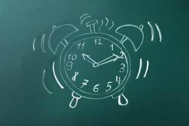 Drawn alarm clock on green chalkboard. School time