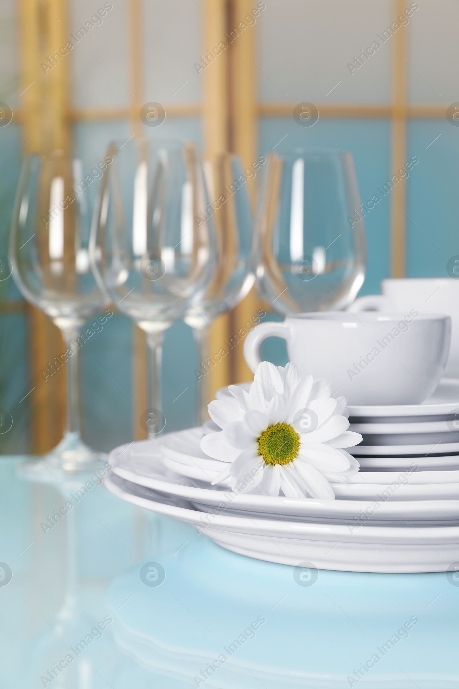 Photo of Set of clean dishware and flower on light blue table, closeup