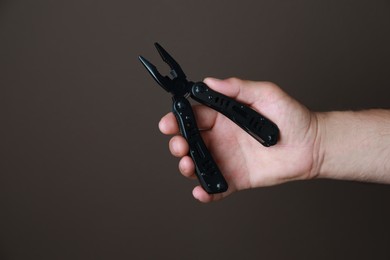 Photo of Man holding multitool on brown background, closeup