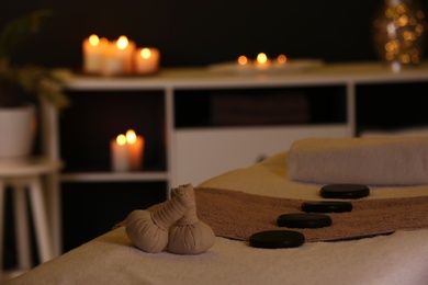 Photo of Herbal compresses and stones on massage table in spa salon