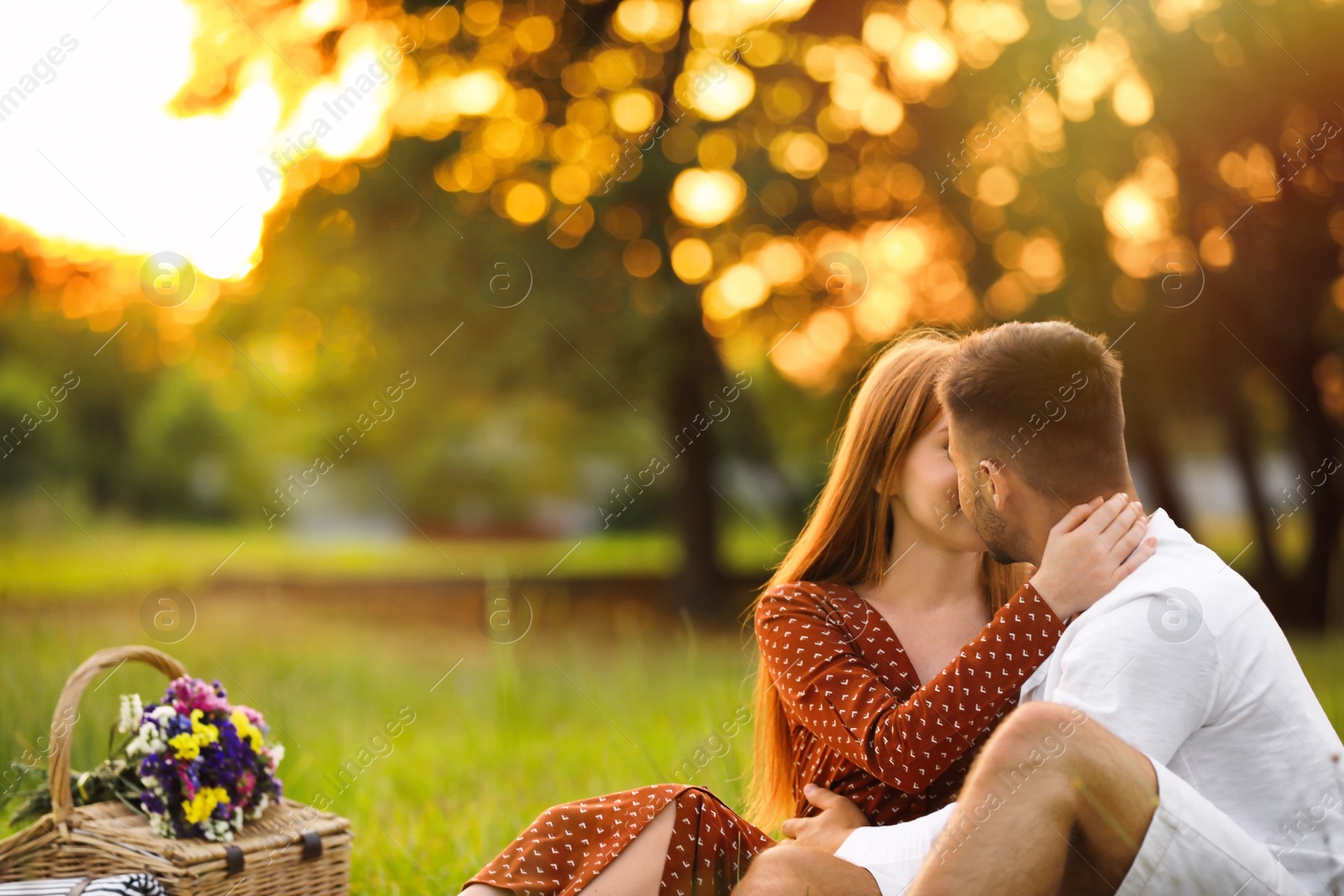 Photo of Happy young couple kissing in park. Picnic season