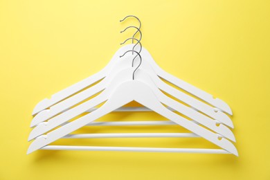 Photo of Many white hangers on yellow background, top view