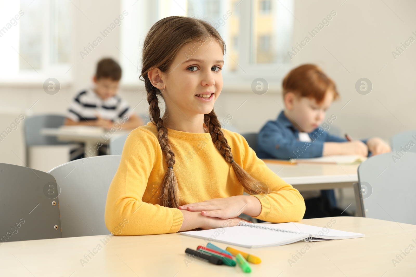 Photo of Portrait of smiling little girl studying in classroom at school