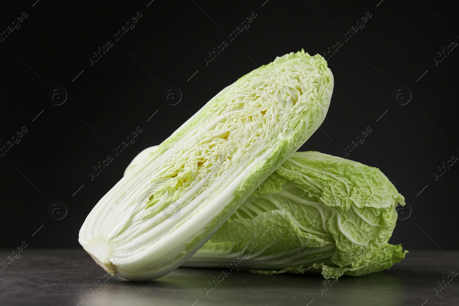 Photo of Whole and cut fresh Chinese cabbages on grey table