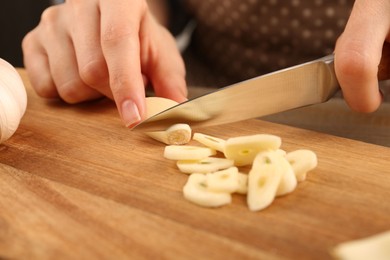 Woman cutting fresh garlic at table, selective focus