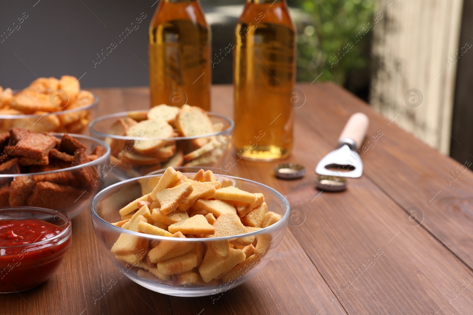 Photo of Different crispy rusks, beer and dip sauce on wooden table