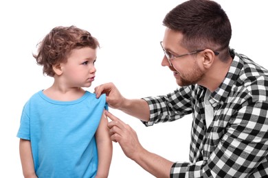 Photo of Father applying ointment onto his son`s shoulder on white background