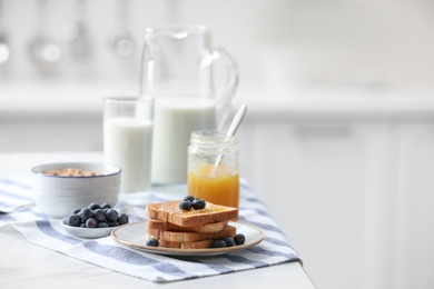 Photo of Toasted bread with jam and blueberries on white marble table in kitchen, space for text