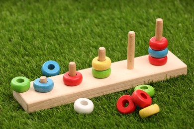 Photo of Stacking and counting game wooden pieces on artificial grass, closeup. Educational toy for motor skills development