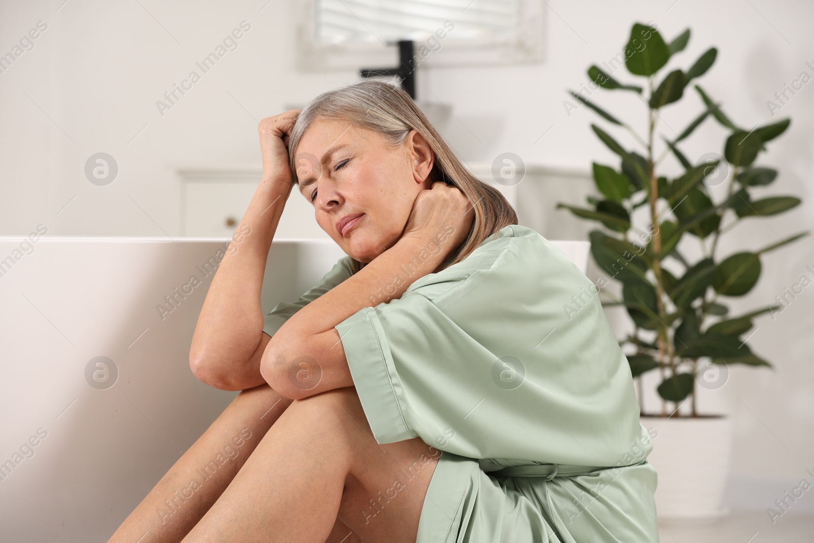 Photo of Menopause. Woman suffering from headache near bath tub in bathroom