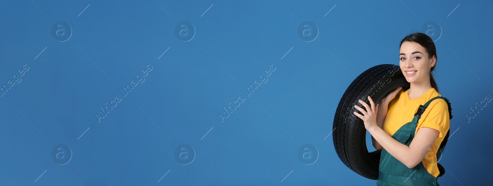 Image of Seller in uniform with car tire on blue background, space for text. Banner design