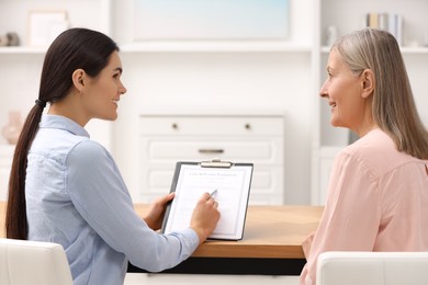 Notary consulting senior woman about Last Will and Testament in office, back view