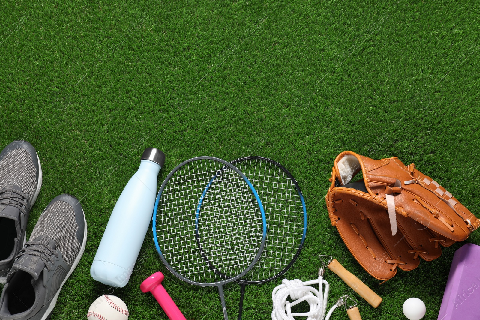 Photo of Different sports equipment on green grass, flat lay. Space for text