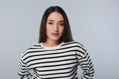 Portrait of beautiful young woman on light grey background