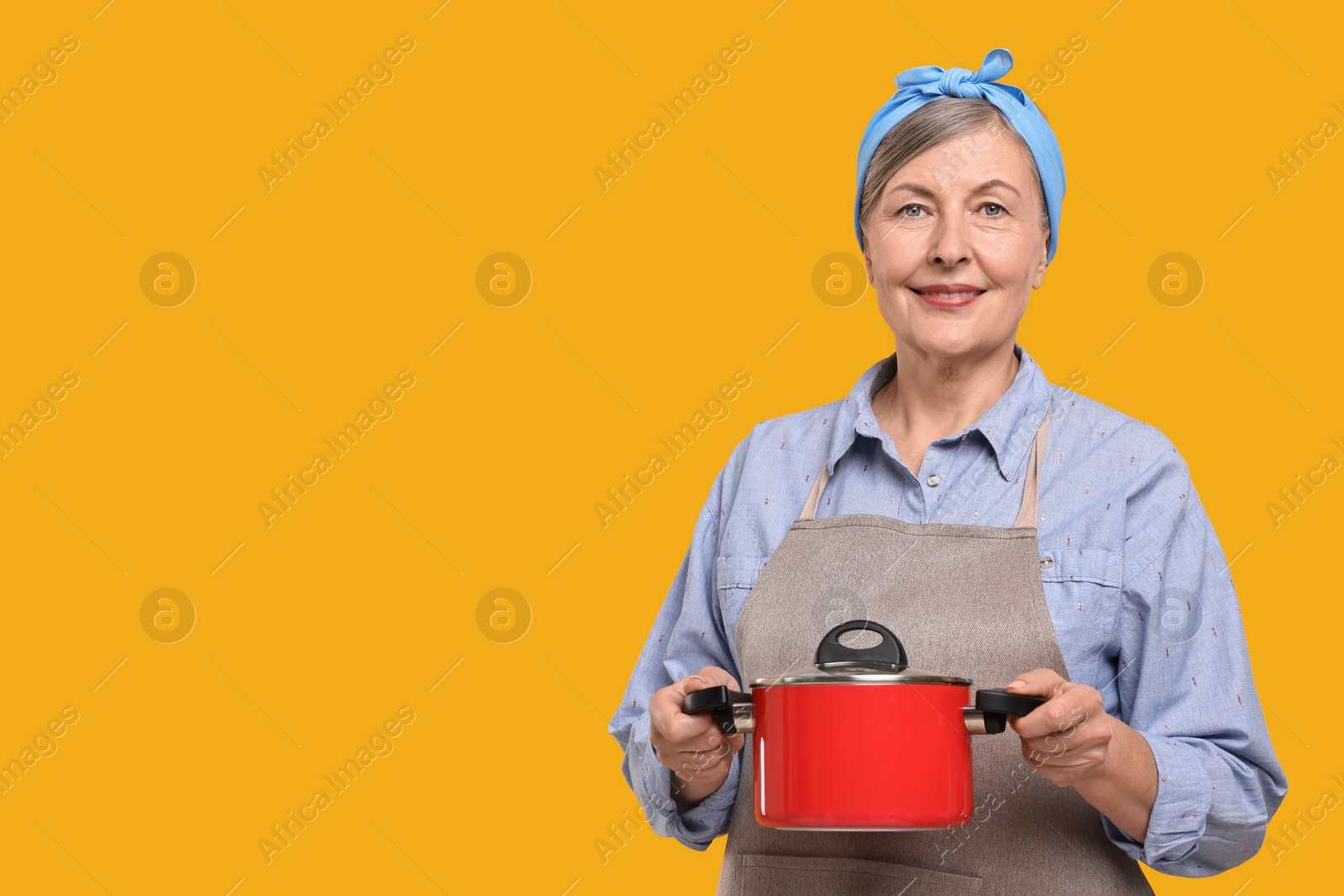 Photo of Happy housewife with pot on orange background, space for text