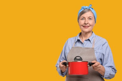 Photo of Happy housewife with pot on orange background, space for text