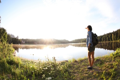 Photo of Young woman on shore of beautiful lake, wide-angle lens effect. Camping season