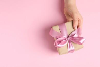 Woman with gift box on pink background, top view. Space for text