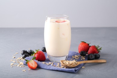 Tasty yogurt in glass, oats and berries on grey table