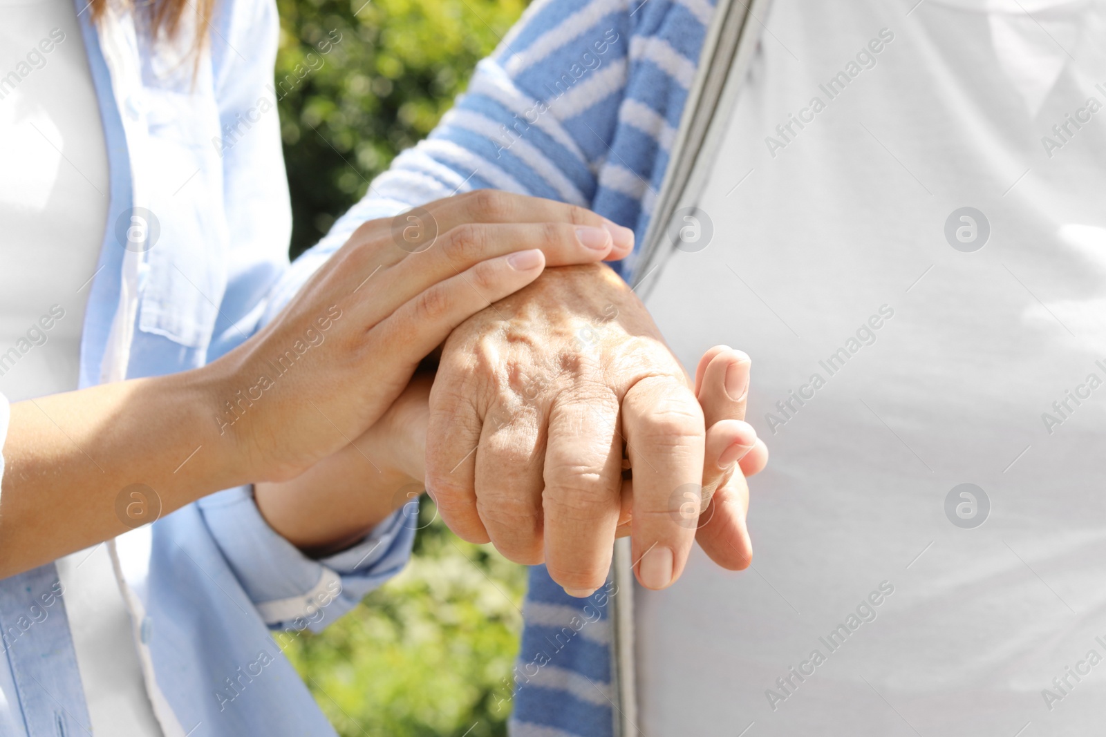 Photo of Helping hands on blurred background, closeup. Elderly care concept